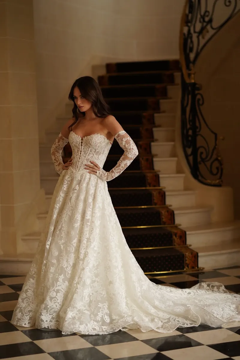 Robe en dentelle Séléstia Charlotte portée avec des gants longs dans un escalier